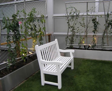 Stainless steel ferrule rope mesh is installed in the yard with a white chair in it.