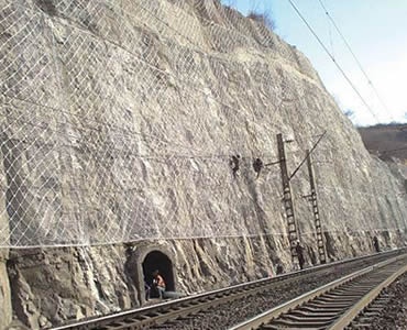A large piece of slope protection rope mesh is covered on slope beside railway.